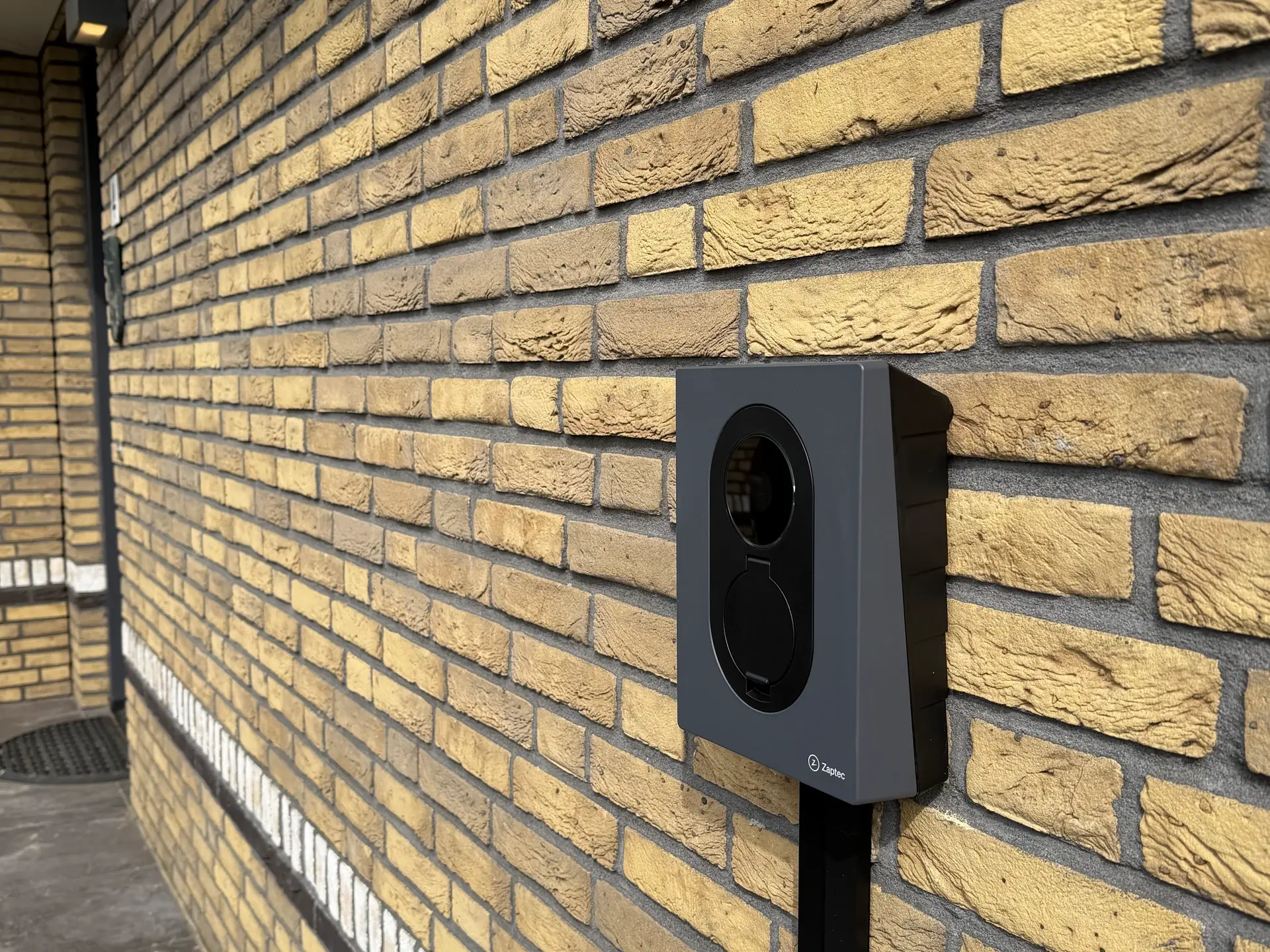 Een laadpunt aan de gemetselde wand met een afgewerkte kabelroute naar beneden.