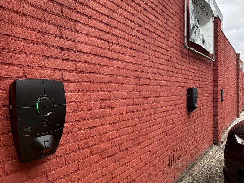 Zaptec Pro gemonteerd aan de gevel bij de sportlocatie, met een volgend laadpunt verderop